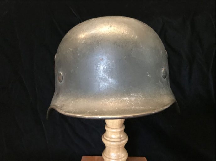 Detailed side view of the WWII German M-35 double decal Field Police helmet, displayed at the museum