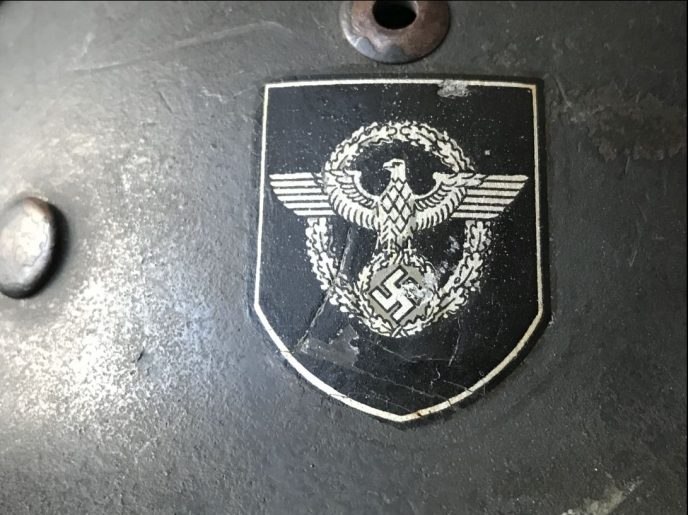 Front and side view of WWII German Field Police helmet, with original decals, displayed at the museum