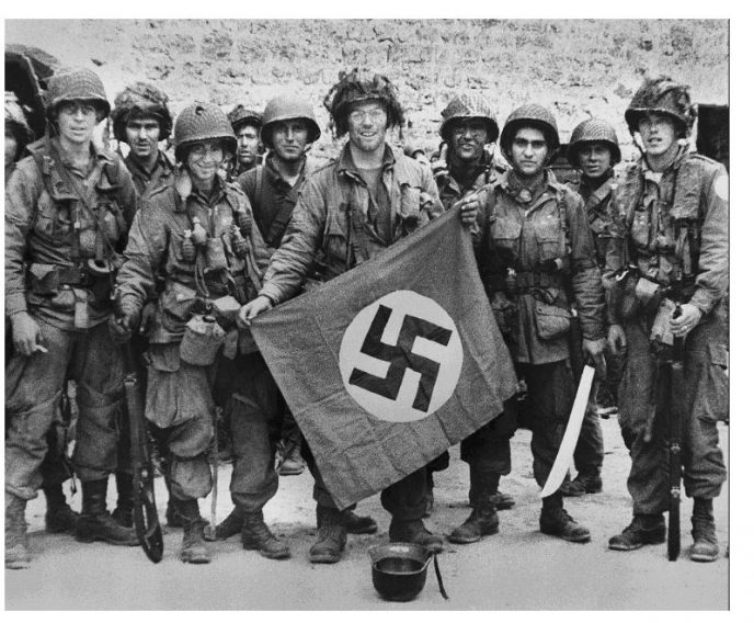 Nazi flag captured by U.S. GI, WWII, displayed with American military equipment